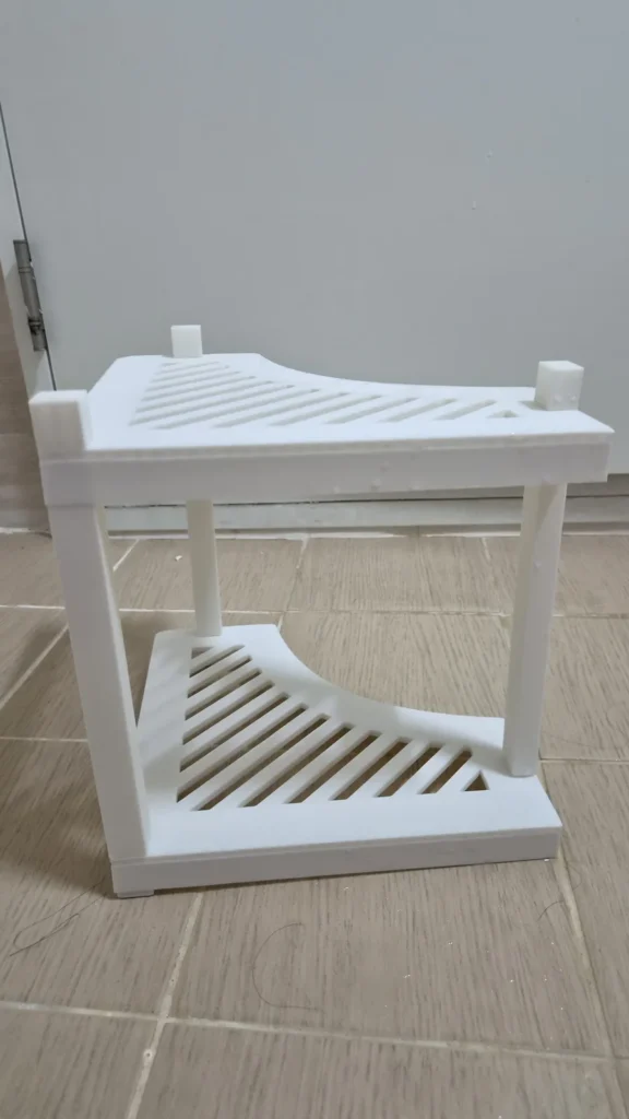 흰색 2단 3D프린트 화장실 모서리 수납함 완성본 정면. 사선 슬릿 선반과 기둥이 보인다