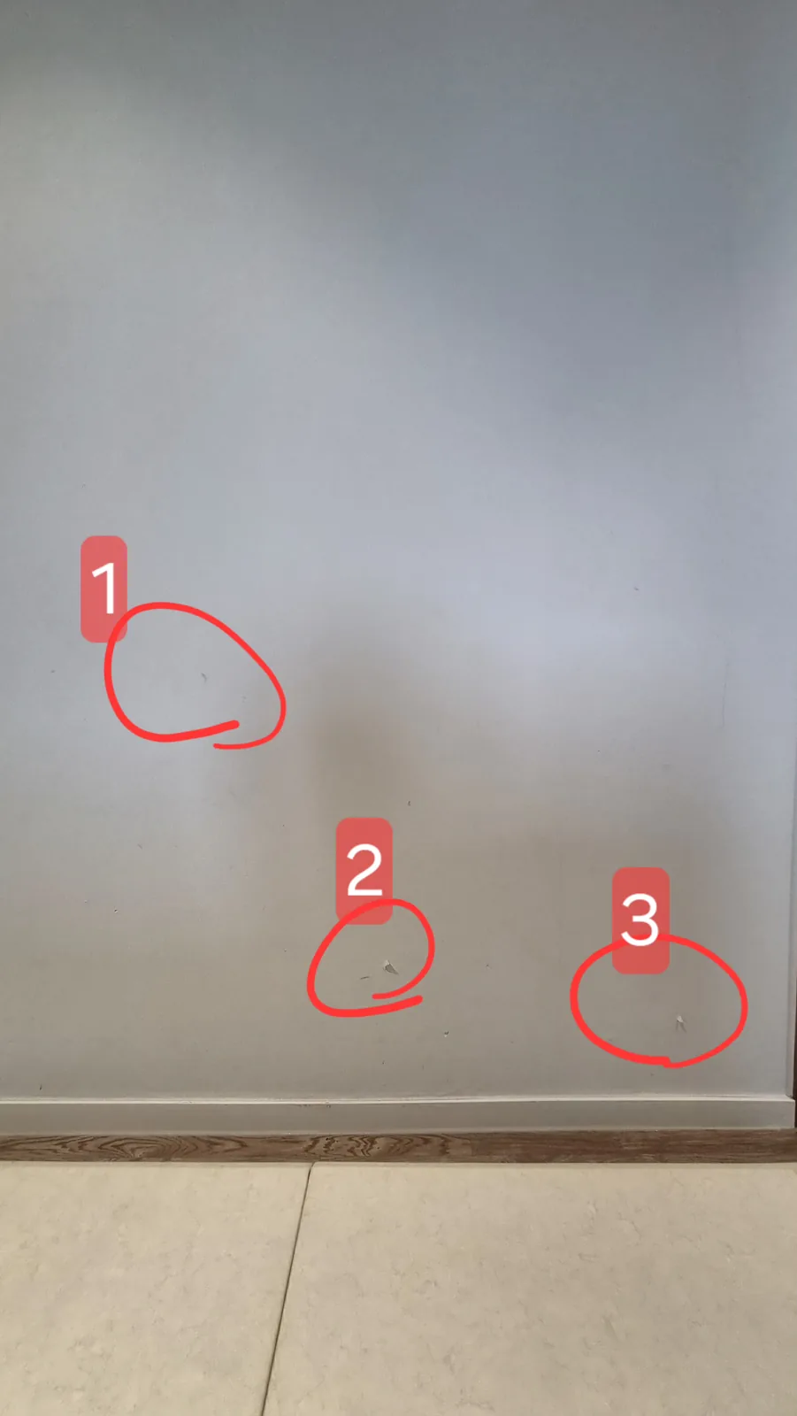 흰 벽에 들뜬 자리 세 곳을 1, 2, 3으로 빨간 원과 번호로 표시한 전경. 아래는 걸레받이와 마루.