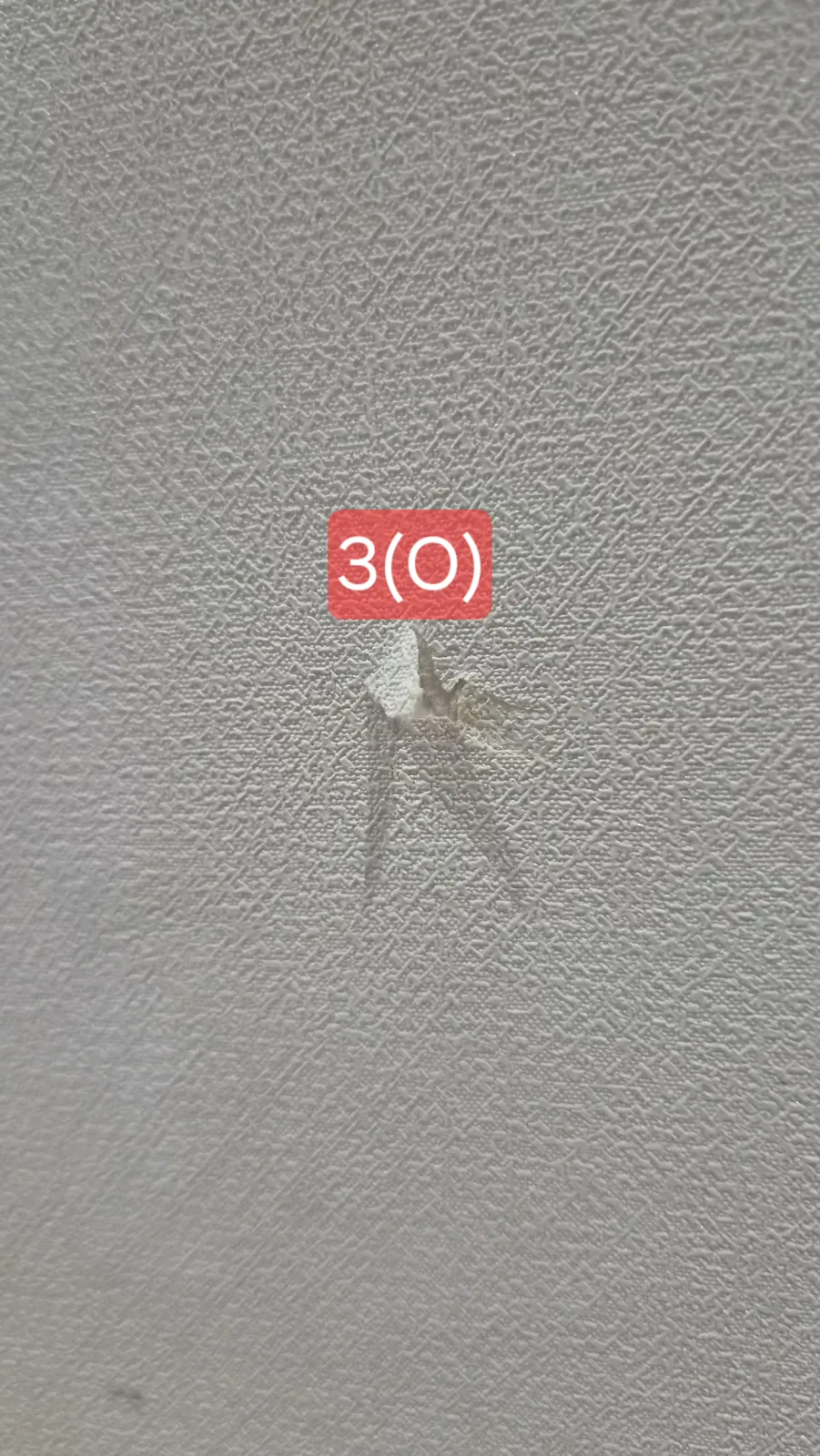 들뜬 벽지 조각이 아직 벽에 붙어 있는 클로즈업. 사진에 3(O) 표시.